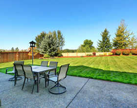 A patio with table and chairs looking out to green grass