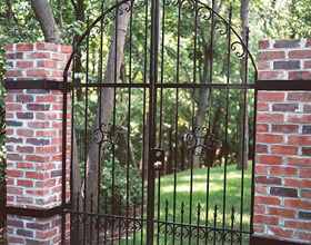 Metal garden gate and brick fence